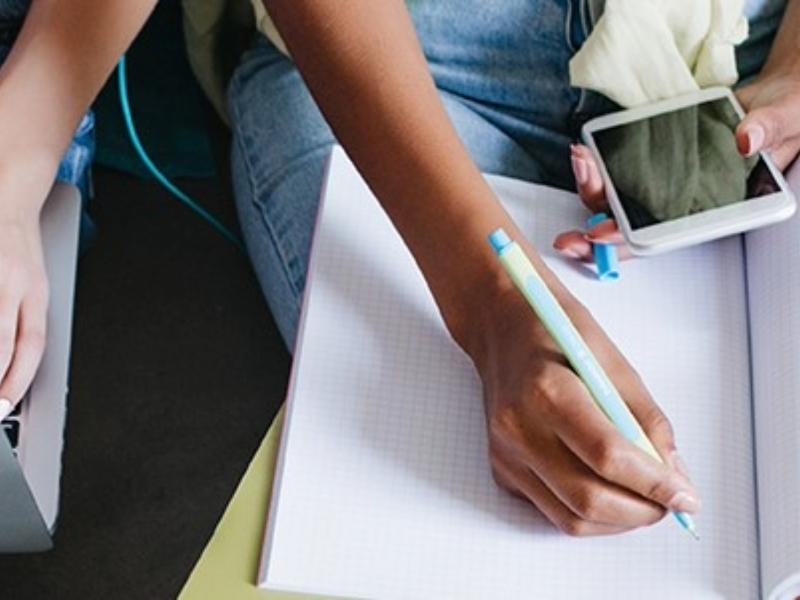 People studying with computers, notebooks, and phones