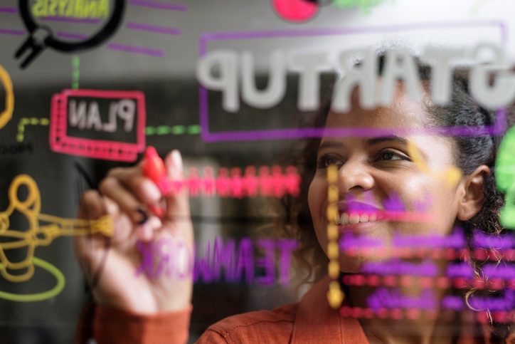 mujer dibujando un mapa mental en un cristal de una oficina. 