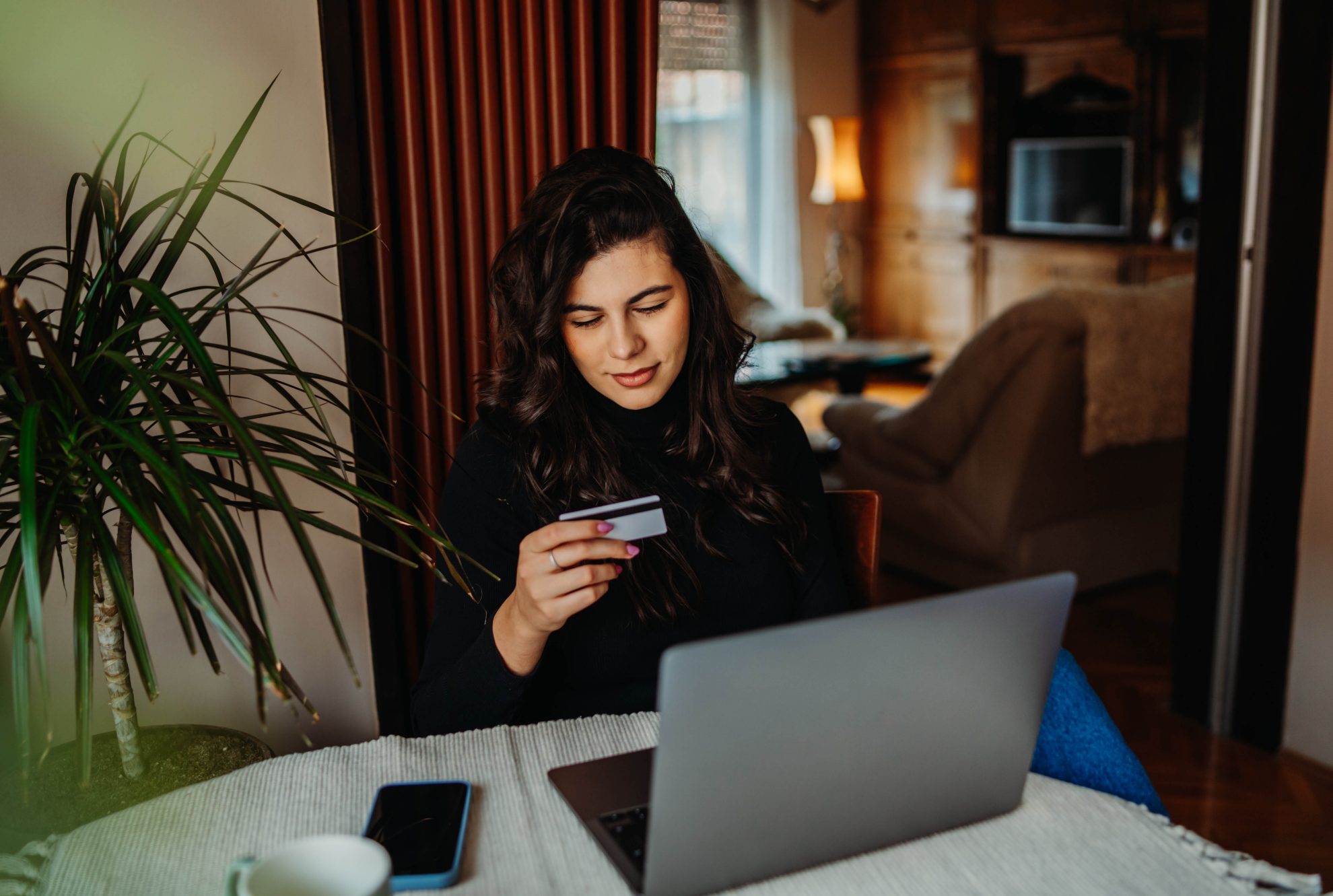 One young caucasian woman is buying online on her laptop using credit card from her home	