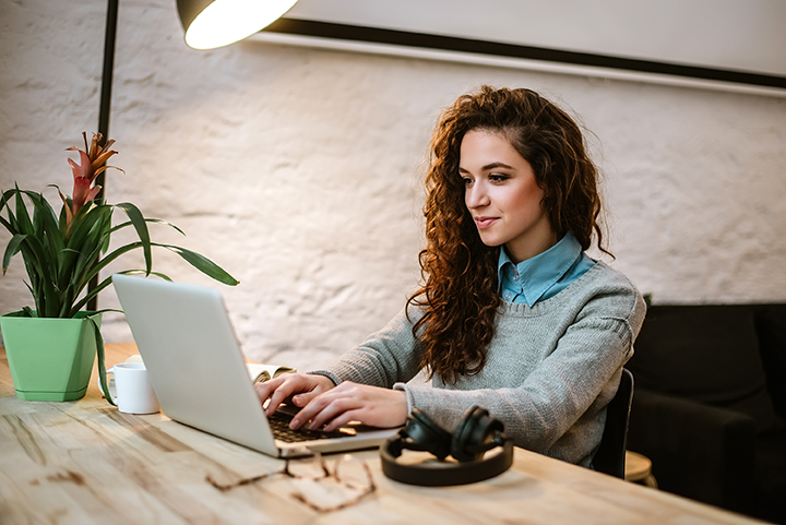 Happy casual entrepreneur working on line typing with a laptop in home office.