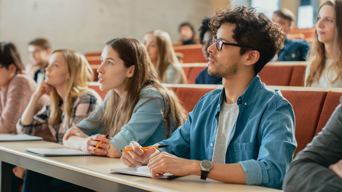 grupo de estudantes em uma sala de aula, aprendendo sobre uma bolsa para faculdade.