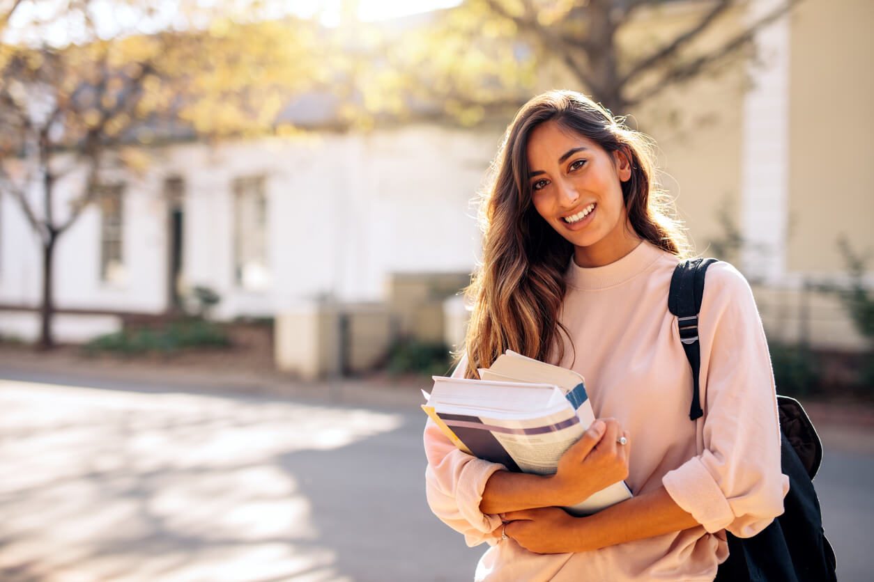Jovem universitária com livros e materiais didáticos contendo informações úteis para programas de estudo. 