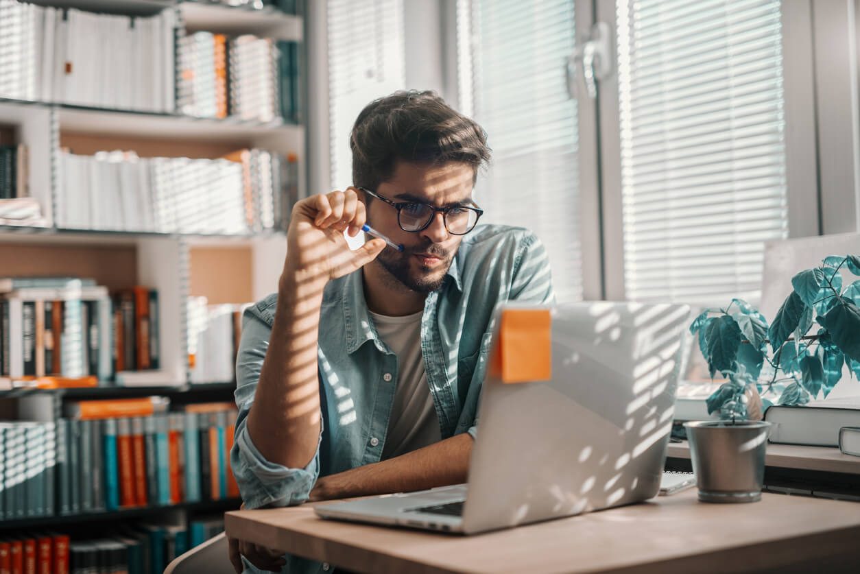 Estudante procurando as melhores opções de programas de estudo na biblioteca da sua faculdade.