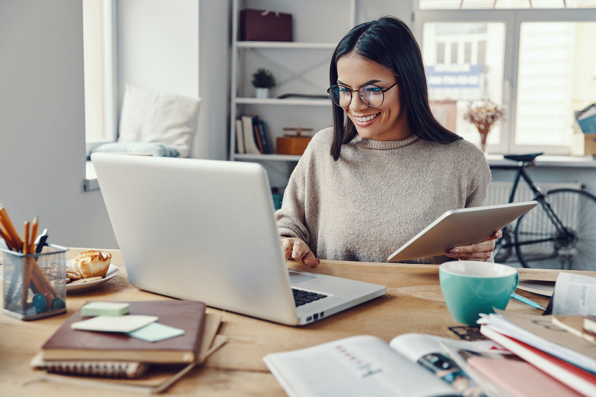 Beautiful young woman in casual clothing using laptop and smiling while working indoors  