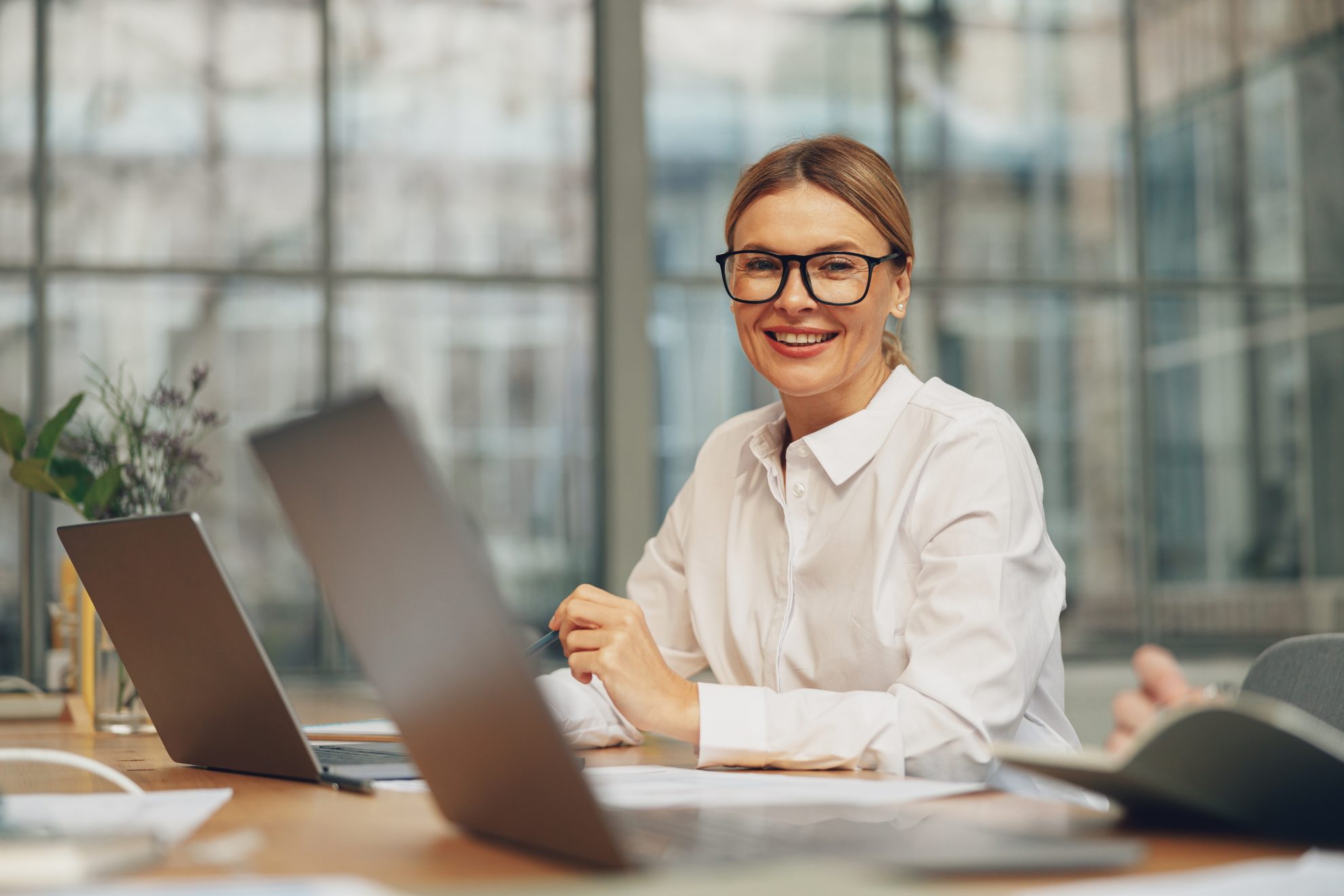 Smiling businesswoman working on laptop while sitting in modern coworking